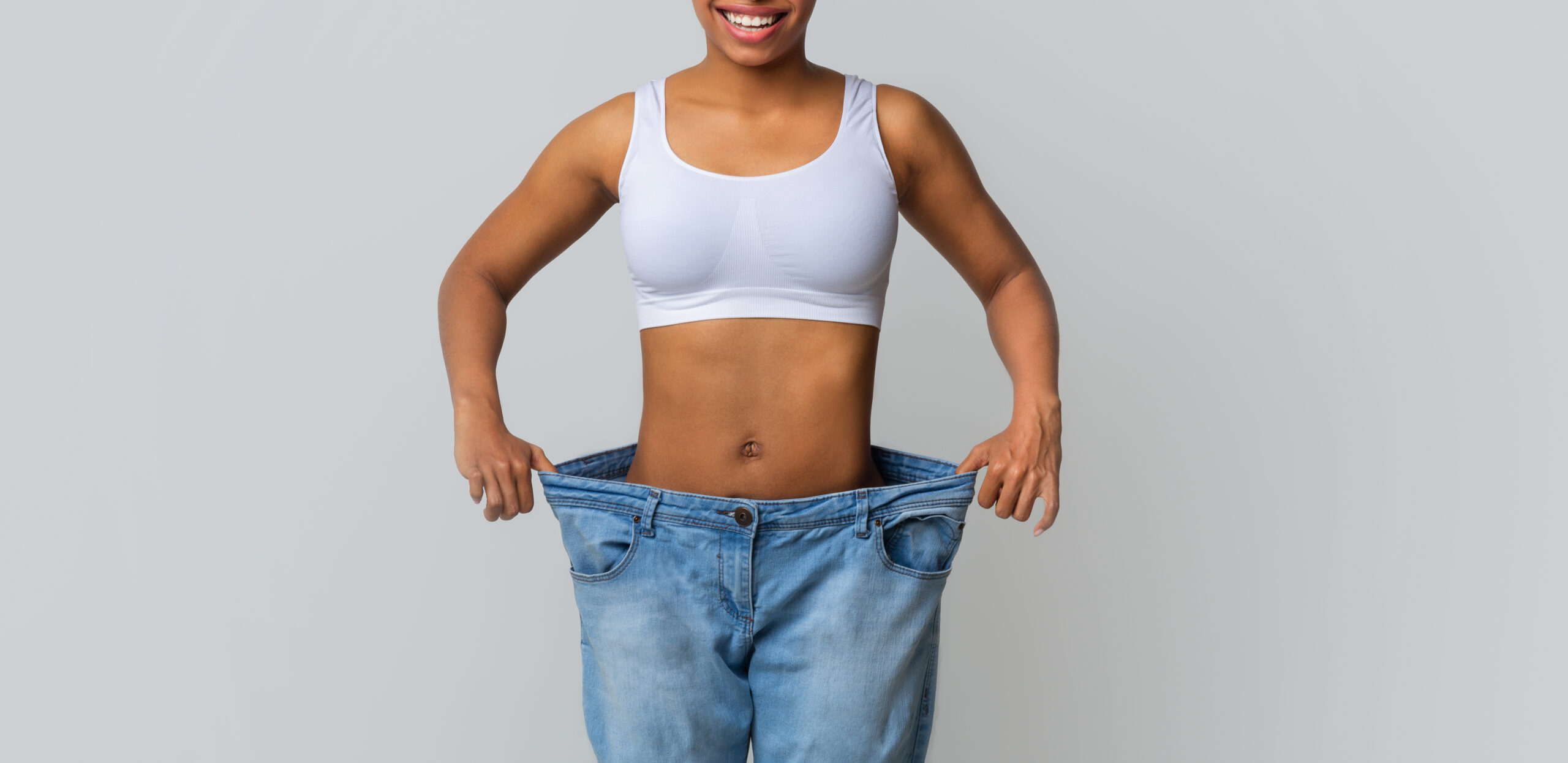 Happy young woman with too large jeans